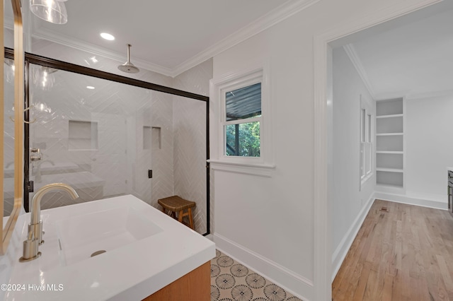 bathroom featuring hardwood / wood-style flooring, an enclosed shower, ornamental molding, and sink