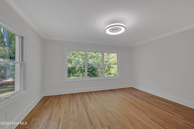 spare room with a healthy amount of sunlight, crown molding, and light hardwood / wood-style floors