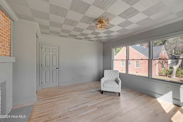 sitting room featuring crown molding, light hardwood / wood-style floors, and a brick fireplace