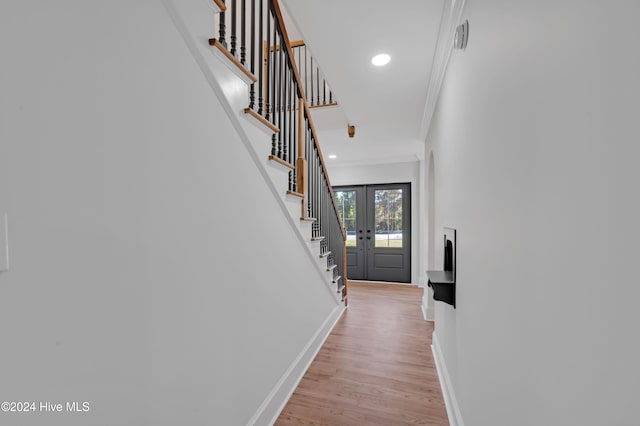 foyer entrance with french doors, ornamental molding, and light hardwood / wood-style flooring