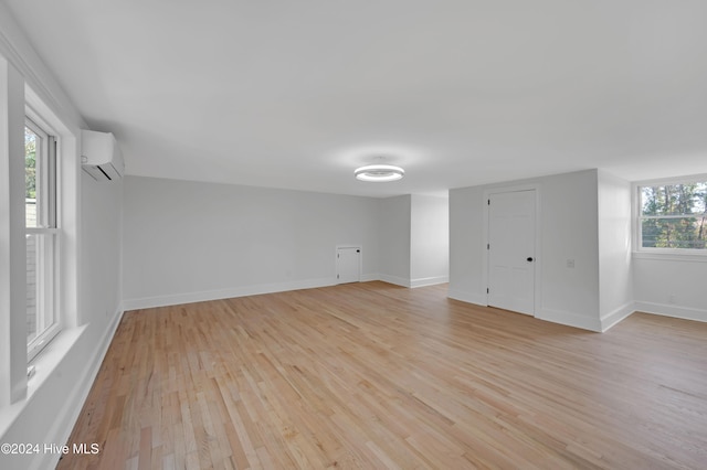 spare room featuring light hardwood / wood-style floors, an AC wall unit, and a wealth of natural light