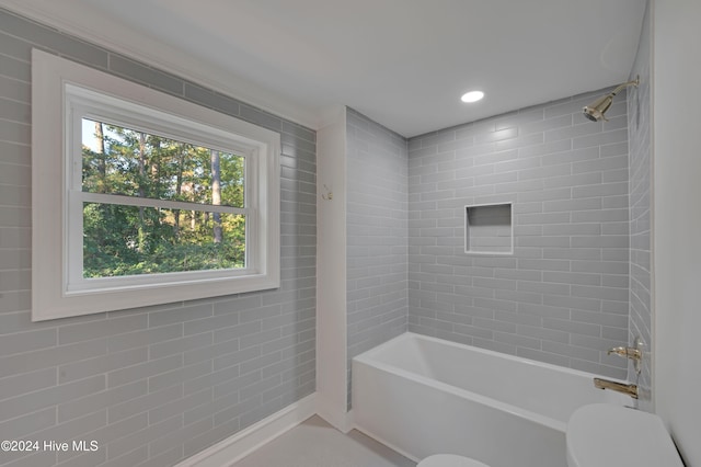 bathroom with tiled shower / bath combo and toilet