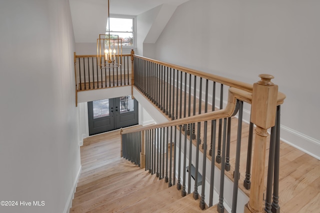 stairs with hardwood / wood-style flooring and an inviting chandelier