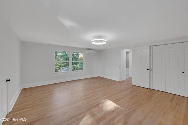 unfurnished room with light wood-type flooring and a wall mounted AC