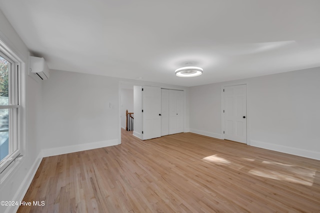 empty room featuring a wall unit AC and light wood-type flooring