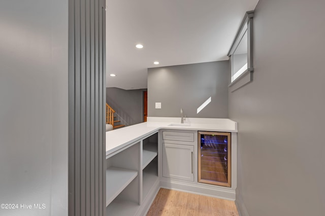 bar with light wood-type flooring, sink, and beverage cooler