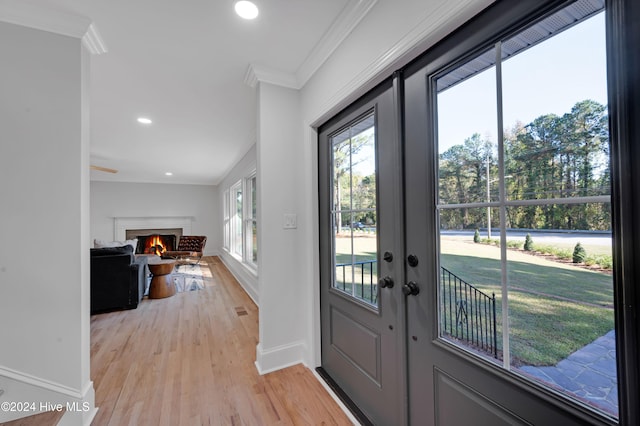 entryway featuring crown molding, plenty of natural light, light hardwood / wood-style floors, and french doors