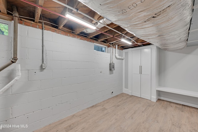 basement featuring electric panel and hardwood / wood-style flooring