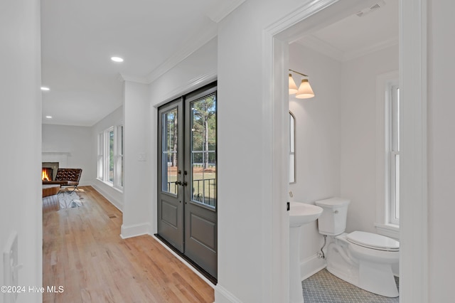 foyer entrance with light wood-type flooring, ornamental molding, and french doors