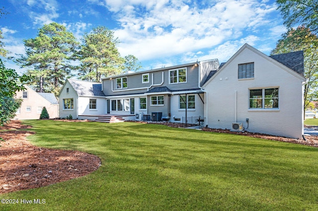 rear view of property with central air condition unit and a lawn