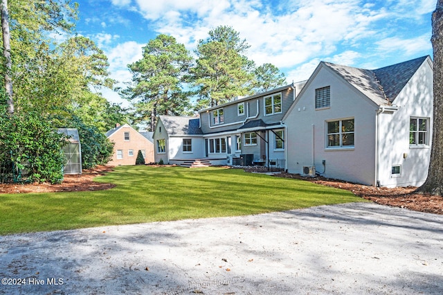 rear view of house featuring an outbuilding and a lawn