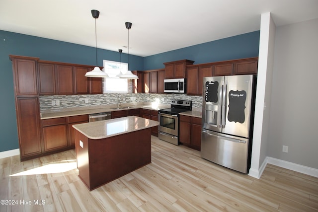 kitchen featuring a center island, sink, hanging light fixtures, stainless steel appliances, and light wood-type flooring