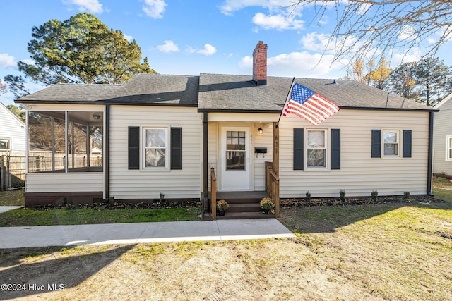 view of front of house featuring a sunroom and a front yard