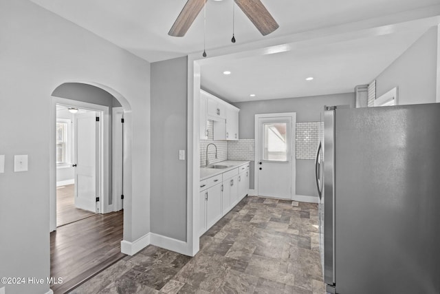 kitchen with sink, ceiling fan, stainless steel fridge, tasteful backsplash, and white cabinetry