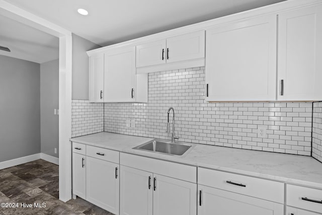 kitchen featuring decorative backsplash, white cabinetry, sink, and light stone counters