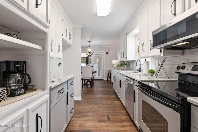 kitchen with white cabinetry, appliances with stainless steel finishes, light stone counters, and decorative light fixtures