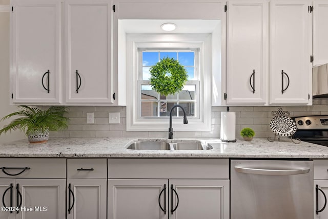 kitchen featuring stainless steel appliances, white cabinetry, a sink, and backsplash