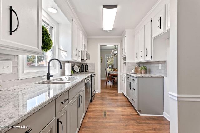 kitchen featuring sink, light stone counters, crown molding, white cabinets, and backsplash