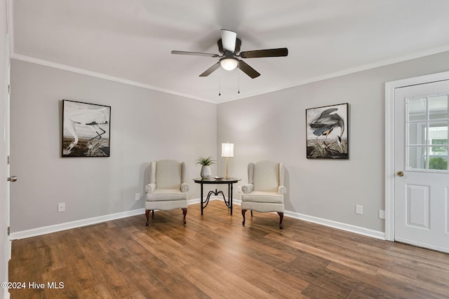 living area with baseboards, wood finished floors, and ornamental molding