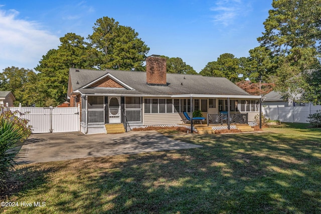 rear view of property featuring a patio, a sunroom, a deck, and a lawn