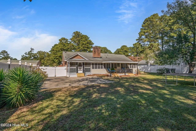 rear view of property with a sunroom, a lawn, a trampoline, and a patio area