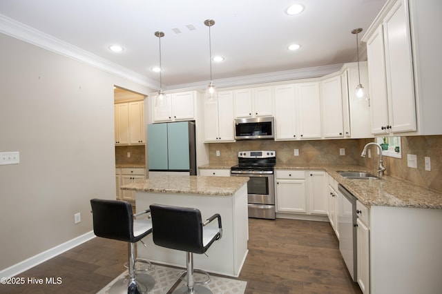 kitchen with sink, a center island, pendant lighting, white cabinets, and appliances with stainless steel finishes