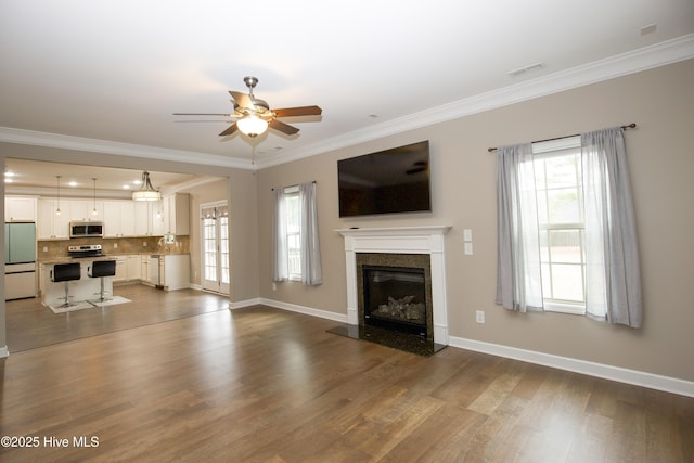 unfurnished living room with ceiling fan, crown molding, a high end fireplace, and dark wood-type flooring