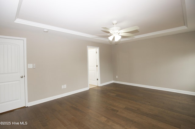 spare room featuring dark hardwood / wood-style floors, a raised ceiling, ceiling fan, and ornamental molding