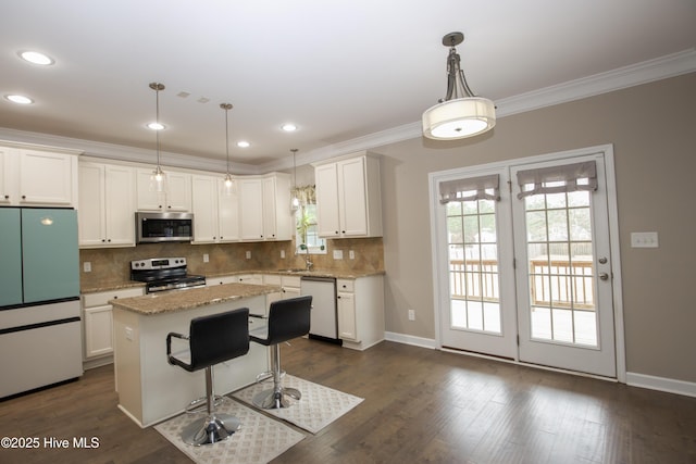 kitchen with white cabinets, decorative light fixtures, a center island, and appliances with stainless steel finishes