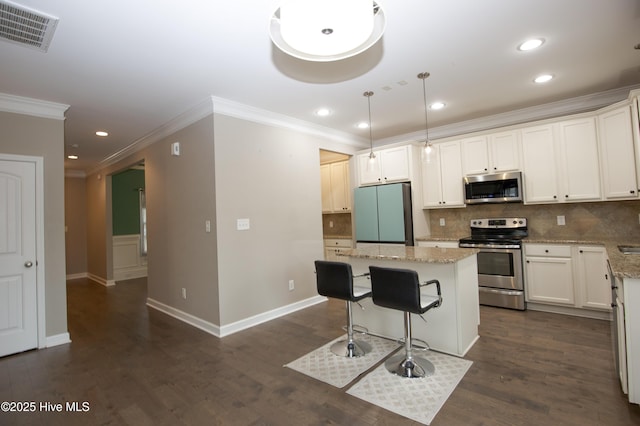 kitchen with light stone countertops, hanging light fixtures, a kitchen island, and stainless steel appliances