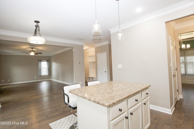 kitchen with ceiling fan, a center island, hanging light fixtures, a kitchen bar, and white cabinets