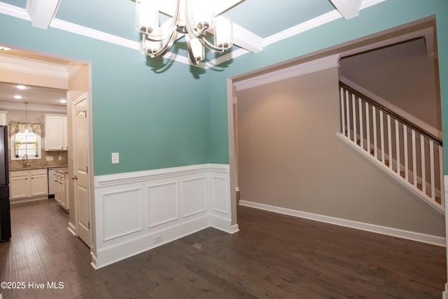 unfurnished dining area with dark hardwood / wood-style flooring, crown molding, a notable chandelier, and sink