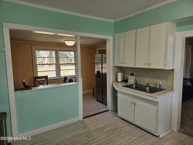 kitchen featuring sink, ornamental molding, stainless steel refrigerator with ice dispenser, and white cabinetry