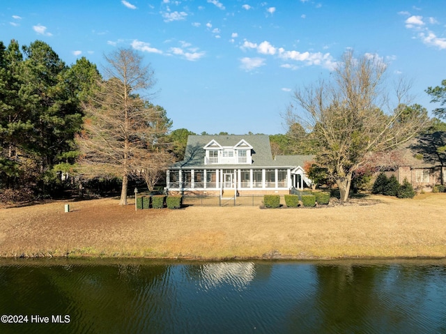 rear view of property with a yard, a water view, and a sunroom