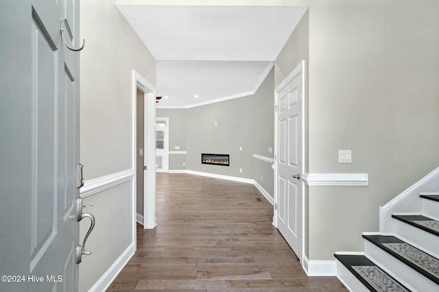 corridor with light hardwood / wood-style floors and ornamental molding