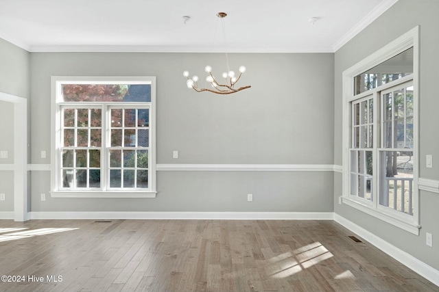 unfurnished dining area with ornamental molding, plenty of natural light, a chandelier, and hardwood / wood-style flooring