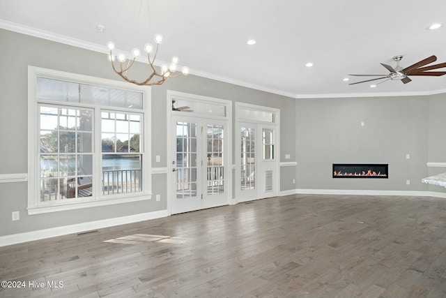 unfurnished living room with ornamental molding, ceiling fan with notable chandelier, and hardwood / wood-style flooring