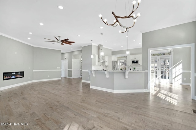 unfurnished living room featuring light wood-type flooring, ceiling fan, and ornamental molding