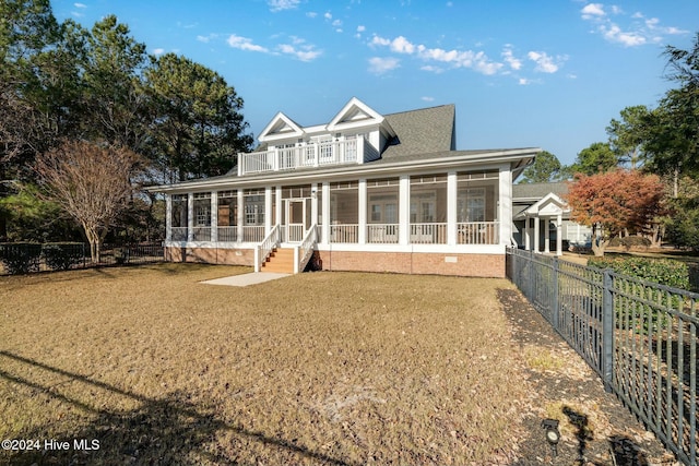 back of property featuring a yard, a sunroom, and a balcony