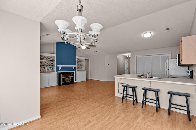 kitchen featuring kitchen peninsula, light hardwood / wood-style floors, lofted ceiling, and a breakfast bar area