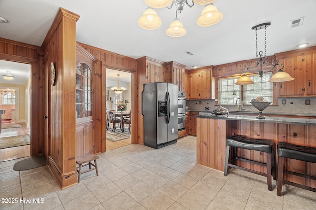 kitchen with pendant lighting, a kitchen breakfast bar, stainless steel refrigerator with ice dispenser, ornamental molding, and light tile patterned floors