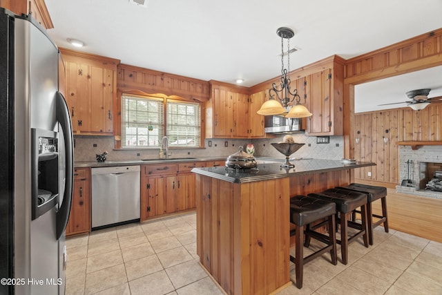 kitchen with appliances with stainless steel finishes, a breakfast bar, sink, light tile patterned floors, and hanging light fixtures