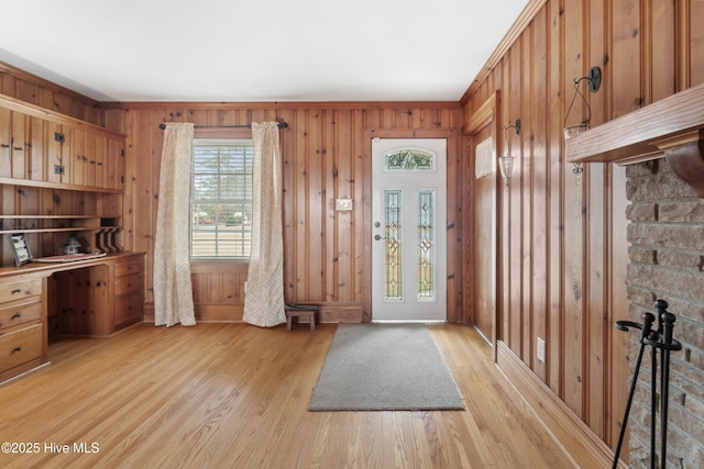 entrance foyer with wooden walls, crown molding, and light hardwood / wood-style floors