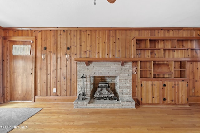 unfurnished living room featuring hardwood / wood-style floors, wooden walls, and a brick fireplace