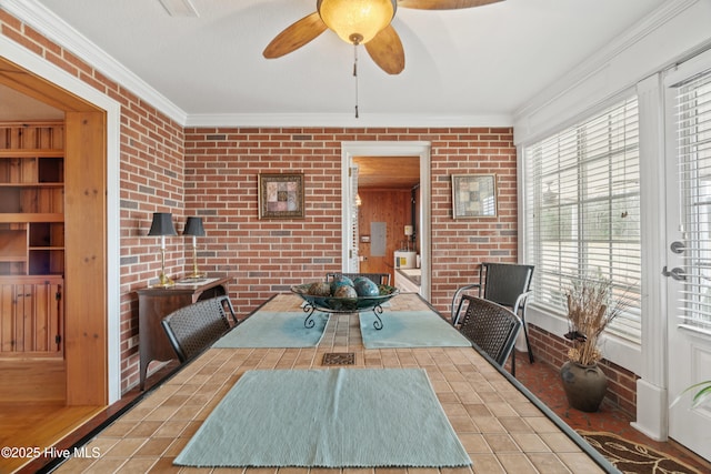 tiled dining room with ceiling fan, ornamental molding, and brick wall