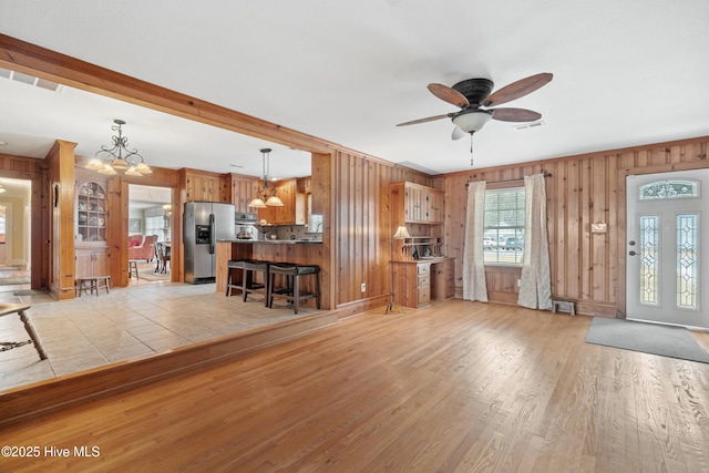 unfurnished living room with ceiling fan with notable chandelier and light wood-type flooring