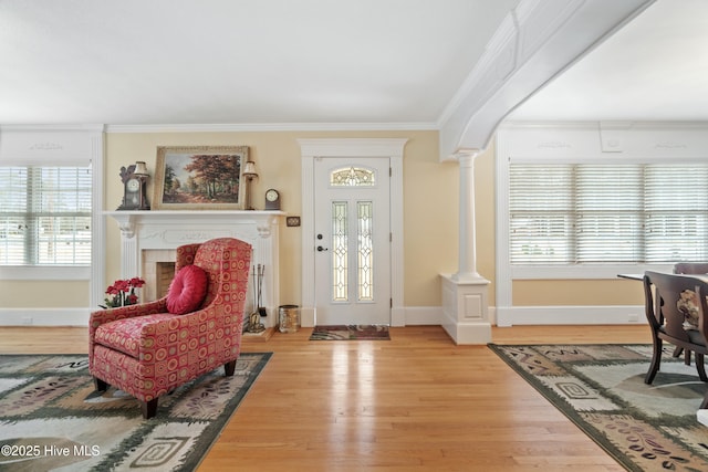 entrance foyer with a tile fireplace, hardwood / wood-style flooring, decorative columns, and crown molding