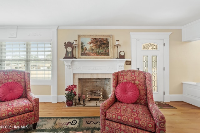 living area with wood-type flooring, ornamental molding, and a tiled fireplace