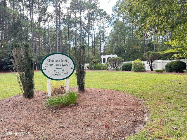 community sign with fence and a yard