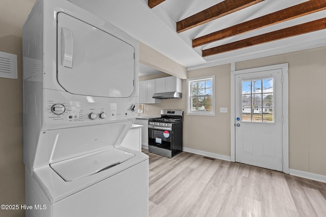 laundry room featuring stacked washer and clothes dryer, light wood finished floors, visible vents, laundry area, and baseboards